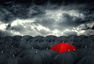 Red umbrella mingling with grey umbrellas - Be different concept